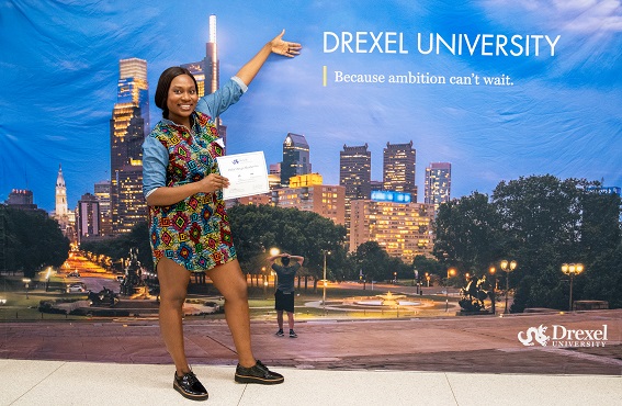 A new Delta Omega inductee in front of a Drexel banner